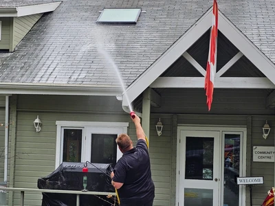 X Wash Exterior Cleaning employee spraying a roof in Hamilton during a roof cleaning service